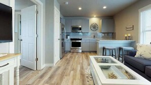 A modern kitchen with white cabinets, a microwave, oven, and a clock on the wall. - Updated bayside condo with heated pool - across the street from the beach (Anna Maria)