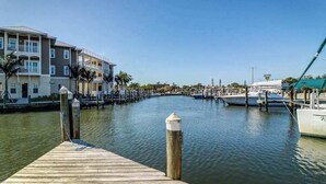 A marina with docked boats, a wooden pier, and a building with balconies. - Stylish bayside condo with WiFi & pool - close to the beach & restaurants (Anna Maria)