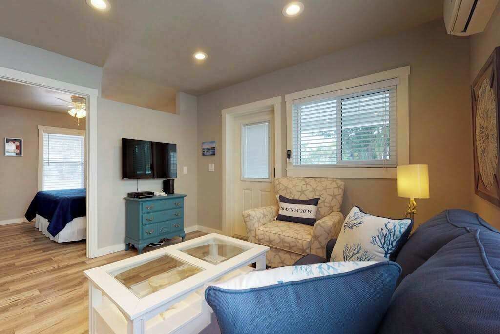 A living room with a television, a patterned armchair, a sofa, a coffee table, and a lamp.