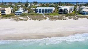 Una zona costiera con proprietà direttamente sulla spiaggia, tra cui un edificio grande con numerosi balconi e una struttura più piccola nelle vicinanze.