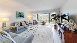 Ein modernes Wohnzimmer mit einer Couch, einem Couchtisch und einem großen Fenster.