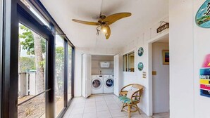 Ein Waschbereich mit Deckenventilator, einem Sessel und Blick durch eine Glastür.