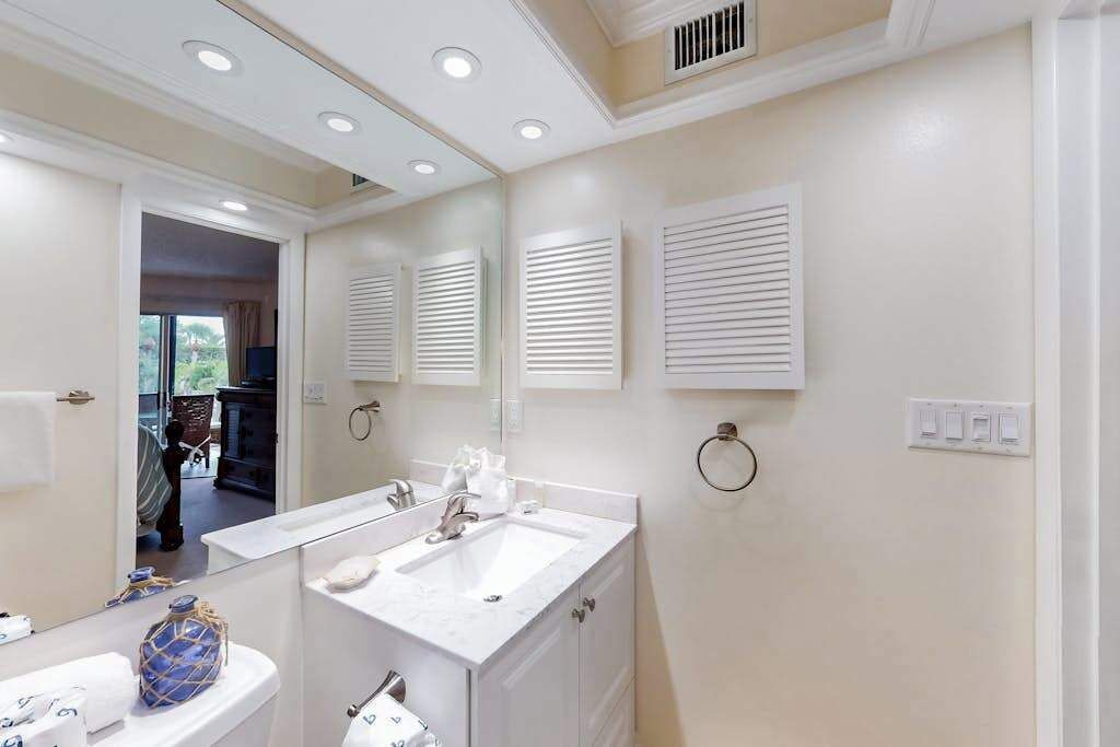 A bathroom with a double sink, a mirror, a towel ring, and a toilet.