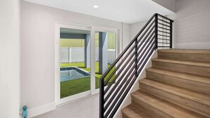 Una escalera con escalones de madera y barandilla de metal negro que lleva a una puerta.