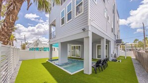 Un edificio de dos pisos con piscina, mobiliario exterior y patio cercado.