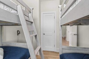 Une pièce avec des lits superposés, une échelle, une porte et un plancher en bois.