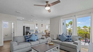 Un salon moderne avec un canapé gris, une table basse et un ventilateur de plafond.