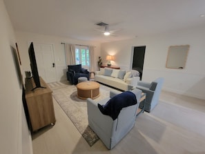 Een woonkamer met een bank, fauteuils, een salontafel en een tv-meubel.