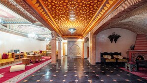 Eine großzügige Lobby mit einem gemusterten Deckenstuck, einem roten Teppich und traditionellen Möbeln.