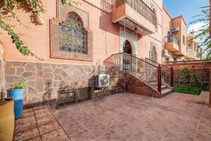 Un bâtiment doté d’une façade en pierre, d’un patio carrelé et d’un escalier avec une rampe en métal.