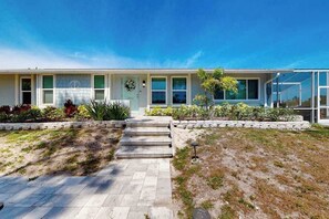 A modern two-story house with a front porch, a small garden, and a clear blue sky. - Sunny canal front home with a pool & dock - central location and dogs ok (Cortez)