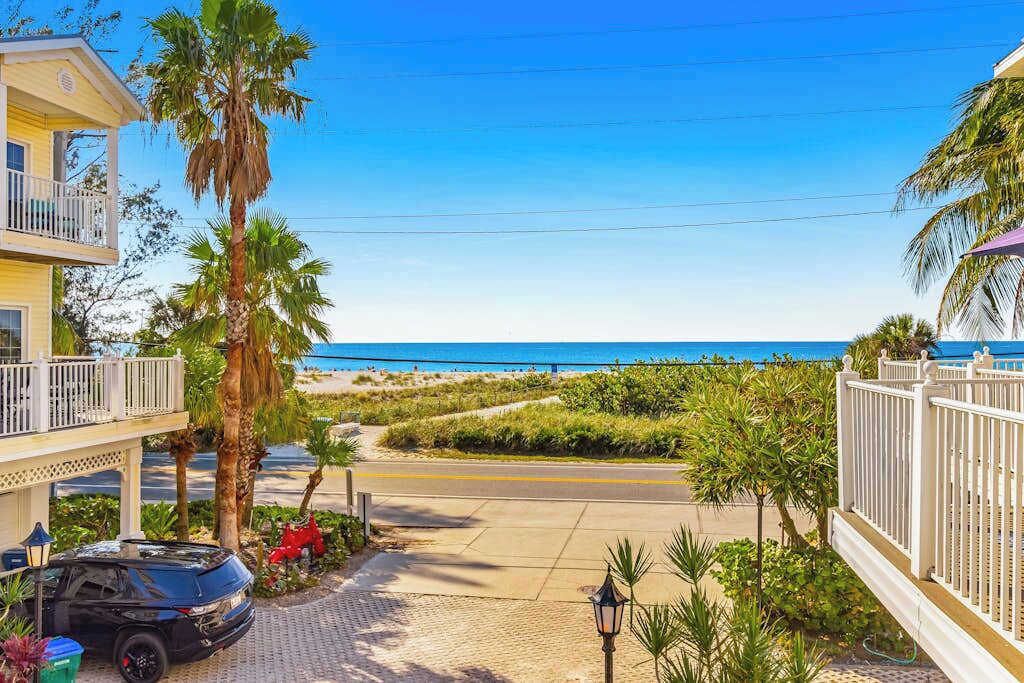 A coastal property with a paved driveway, a parked car, and a view of the beach.