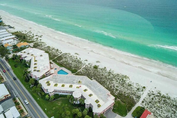 Eine Luftaufnahme eines Küstenhotels mit mehreren Gebäuden, einem Pool und einem Strand.
