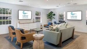 Een moderne woonkamer met een bank, stoelen, een salontafel en een groot raam.