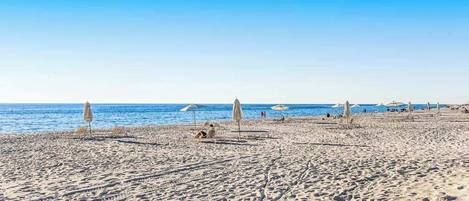 Una playa con sombrillas y tumbonas.