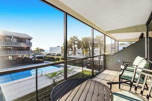 A balcony with a pool, outdoor seating, and a view of the surrounding area. - Seaside family-friendly condo with WiFi, pool & prime location (Holmes Beach)
