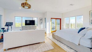 Ein modernes Schlafzimmer mit einem großen Bett, einem Fernseher und einem Balkon mit Blick.