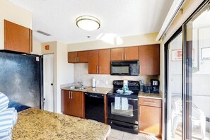 A compact kitchen with a refrigerator, microwave, stove, and dishwasher. - Inviting Condo with Shared Pool, High-Speed WiFi, and Central AC (Holmes Beach)