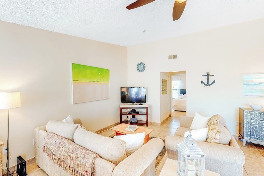 A modern living room with a sofa set, a television, and a decorative anchor on the wall.