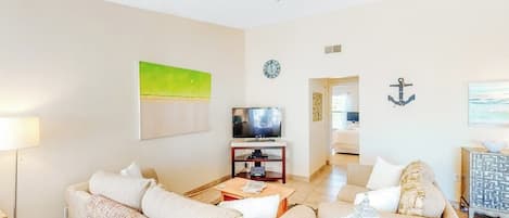 A modern living room with a sofa set, a television, and a decorative anchor on the wall.