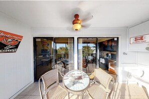 A room with a glass door leading to an outdoor area, a ceiling fan, and a table with chairs. - Inviting Condo with Shared Pool, High-Speed WiFi, and Central AC (Holmes Beach)