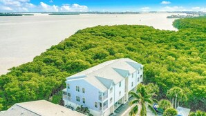 Uma propriedade costeira com um edifício grande, rodeada por vegetação densa e vista para o mar.