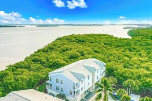 A coastal property with a large building surrounded by dense greenery and a view of the sea. - Inviting Condo with Shared Pool, High-Speed WiFi, and Central AC (Holmes Beach)