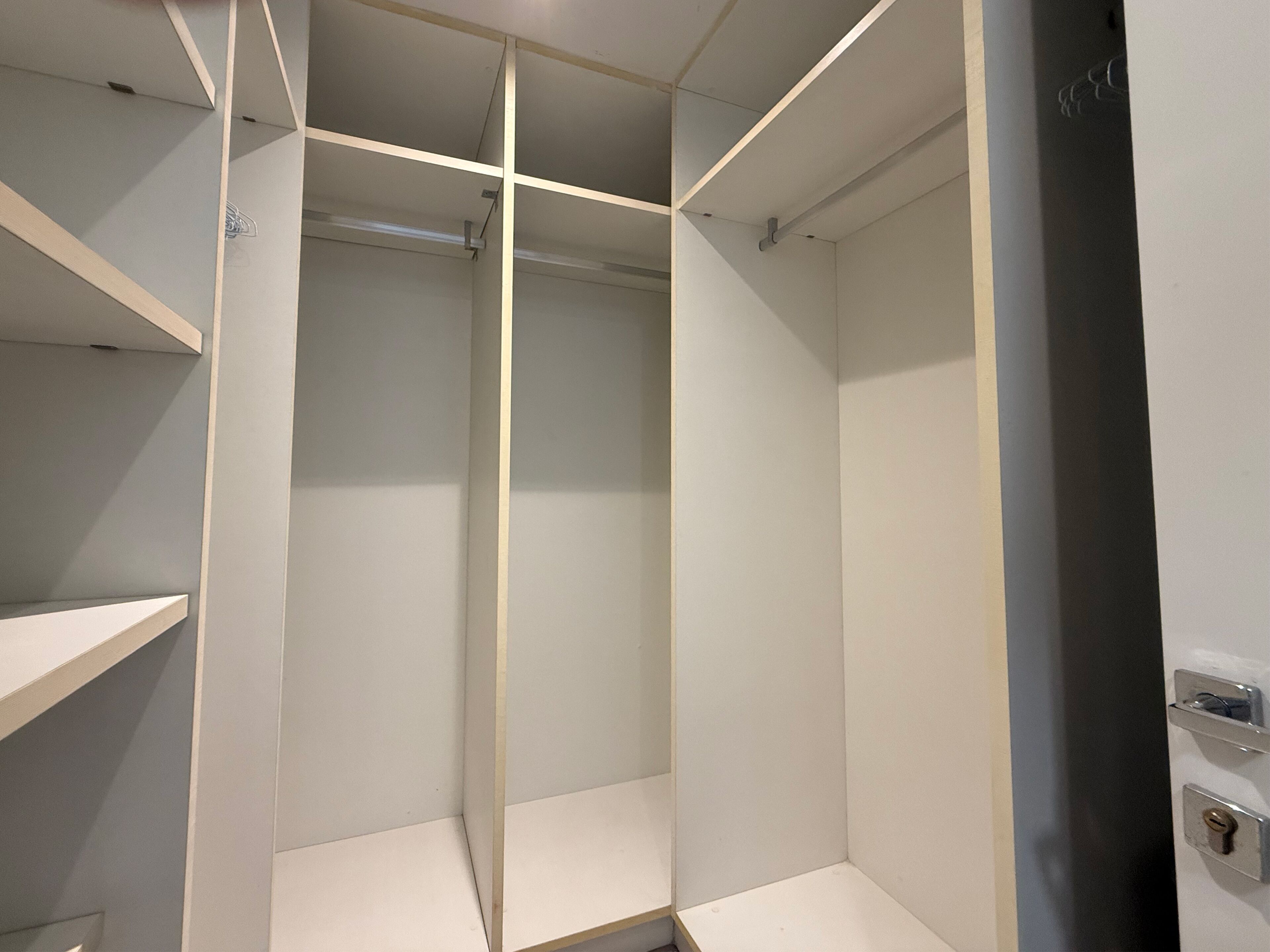 Een kamer met een inbouwkast, een deur met slot en een plankunit.