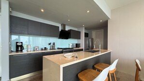 Una cocina moderna con armarios oscuros, una isla central, taburetes de bar y un horno empotrado.