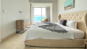 Un dormitorio con una cama grande, un aparador de madera, una silla y vistas al mar.