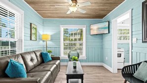 A room with a brown leather sofa, a wooden coffee table, a ceiling fan, and light blue walls. - Charming Suite w Shared Pool, High-Speed WiFi - Steps to the Beach (Siesta Key)