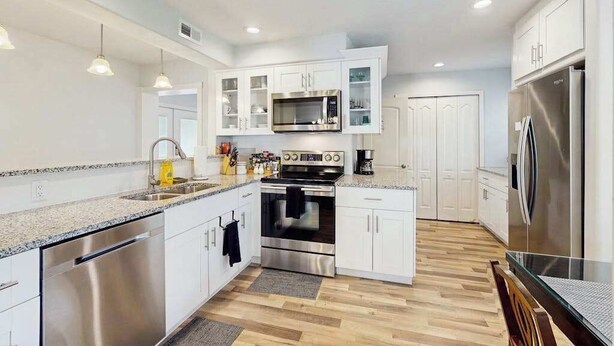 A modern kitchen with white cabinets, stainless steel appliances, and a granite countertop. - Charming home w large yard, near Beaches, Sarasota, Bradenton, & the airport (Sarasota)