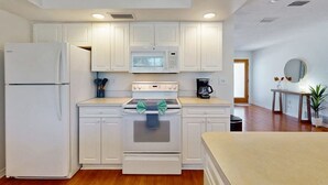 Une cuisine de taille réduite, avec des meubles blancs, un four à micro-ondes, une cuisinière et un réfrigérateur.