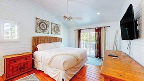 A bedroom with a bed, wooden floor, ceiling fan, artwork, and a TV. - Canal-front home near Shell Beach with access to bay & deck (Sarasota)