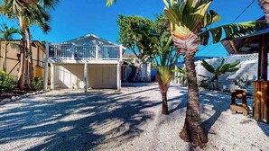 A house with a covered patio, palm trees, and a gravel driveway. - Canal-front home near Shell Beach with access to bay & deck (Sarasota)