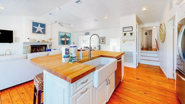 A kitchen with a wooden countertop, white cabinets, and a built-in sink. - Canal-front home near Shell Beach with access to bay & deck (Sarasota)