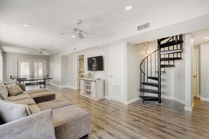 A modern living room with a sectional sofa, a flat-screen TV, a staircase, and a dining area with a table and chairs. - Relaxing Home with Private Pool, High-Speed WiFi, Central AC, & Washer-Dryer (Anna Maria)