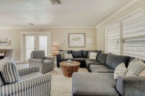 Ein Wohnzimmer mit einer Eckcouch, gestreiften Sessel und einem runden Couchtisch.