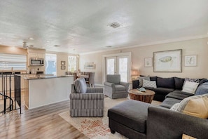A spacious living area with a dark grey sofa, a striped armchair, and a dining table set for four. - Relaxing Home with Private Pool, High-Speed WiFi, Central AC, & Washer-Dryer (Anna Maria)