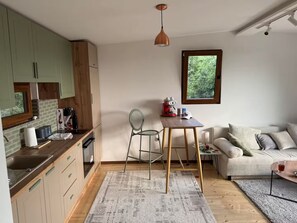 Un espacio habitable compacto con kitchenette, comedor y sofá.