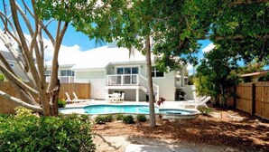 Uma casa com piscina, deck de madeira e quintal cercado.