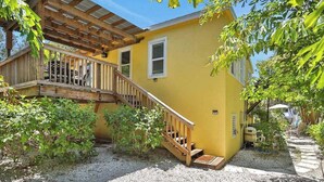 A yellow building with a wooden deck and stairs leading to a covered porch. - Walk-up suite with on-site pool, private deck, full kitchen - walk to beach (Bradenton Beach)