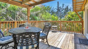 A wooden deck with a table and chairs, surrounded by a wooden railing, overlooking a lush green landscape. - Walk-up suite with on-site pool, private deck, full kitchen - walk to beach (Bradenton Beach)
