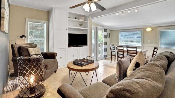A living room with a ceiling fan, a TV, a dining area, and a fireplace. - Walk-up suite with on-site pool, private deck, full kitchen - walk to beach (Bradenton Beach)