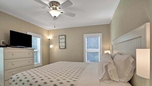 A bedroom with a bed, a ceiling fan, a TV on a dresser, and two windows with blinds. - Walk-up suite with on-site pool, private deck, full kitchen - walk to beach (Bradenton Beach)