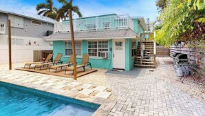 A two-story building with a pool, lounge chairs, and a barbecue area. - 2nd-floor duplex near beach with heated pool, balcony, grill, WD (Bradenton Beach)