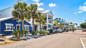 A street with buildings, including a blue building with a sign 'BLUENET' and a white building with balconies. - 2nd-floor duplex near beach with heated pool, balcony, grill, WD (Bradenton Beach)