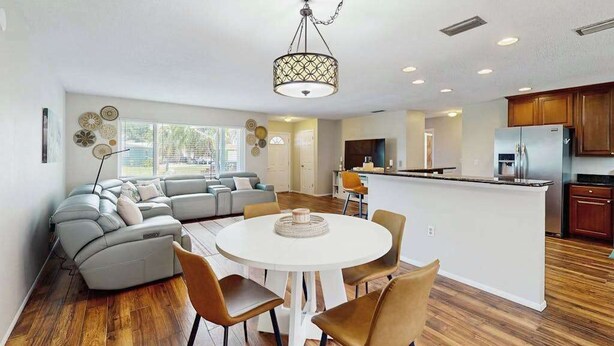 A modern kitchen with a central island, a dining area with a round table and chairs, and a living area with a sofa and a coffee table. - Cozy home with private pool, lanai,  washer & dryer - minutes to beaches (Bradenton)