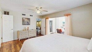 A bedroom with a large bed, a ceiling fan, a dresser, and a view of the outside. - Cozy home with private pool, lanai,  washer & dryer - minutes to beaches (Bradenton)