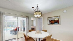 A dining area with a round table, chairs, and a hanging light fixture. - Cozy home with private pool, lanai,  washer & dryer - minutes to beaches (Bradenton)